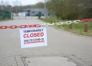 A sign hanging from a red and white chain that says "temporarily closed due to COVID-19